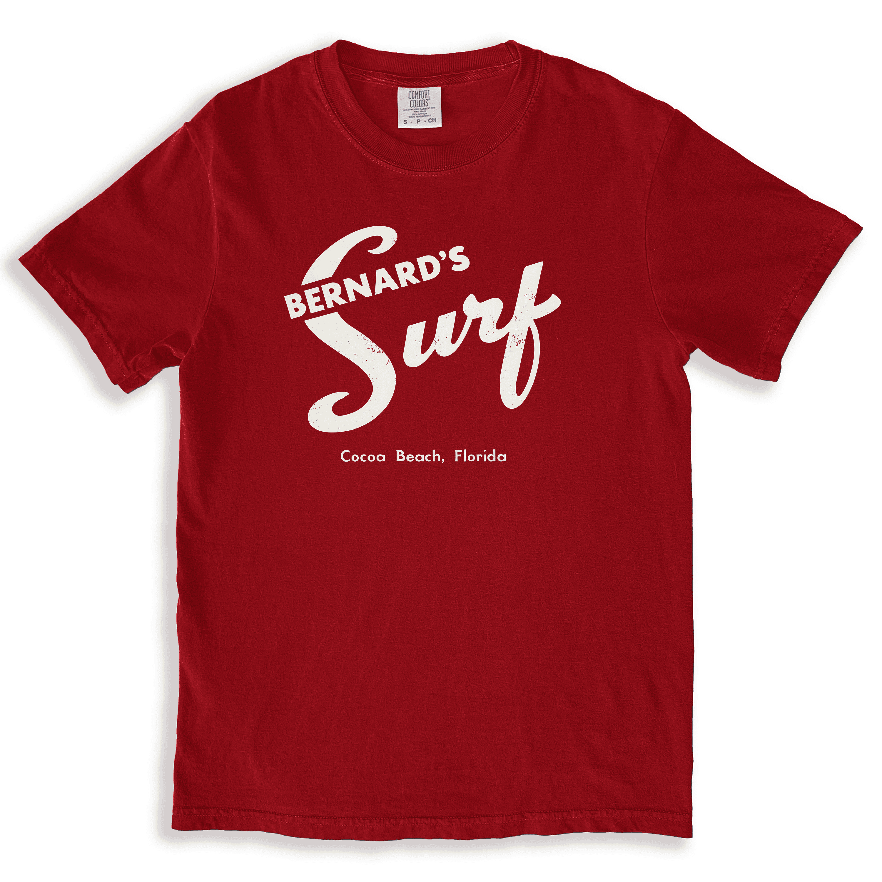 Vintage red T-shirt featuring the classic matchbook-style logo of Bernard's Surf, a historic seafood restaurant in Cocoa Beach, Florida. The design showcases retro white script with 'Bernard's Surf' and 'Cocoa Beach, Florida,' honoring the iconic eatery once popular with astronauts and locals alike.